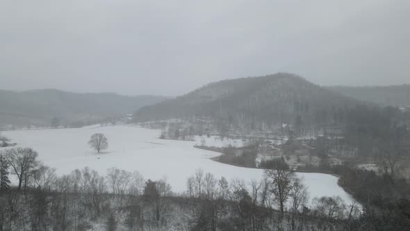 Drone view through farm field in valley in western Wisconsin with mountains and church.