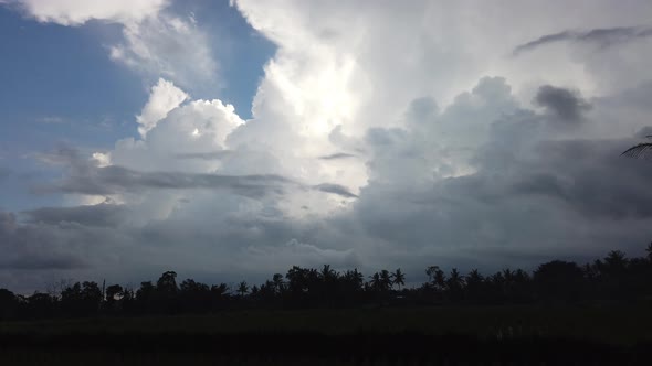 Day to night time lapse big clouds running on blue sky over rice field and palm trees Bali Indonesia