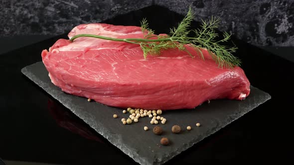 tenderloin veal meat for steaks fillet mignon with spices and greens on black board.