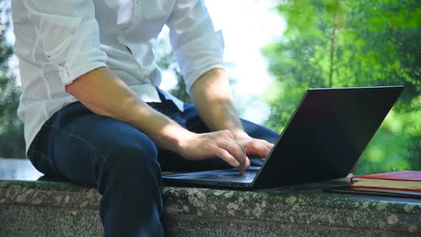 Student Sitting In Park And Working With Laptop
