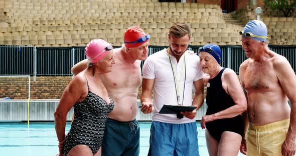 Swim coach training seniors on digital tablet alt