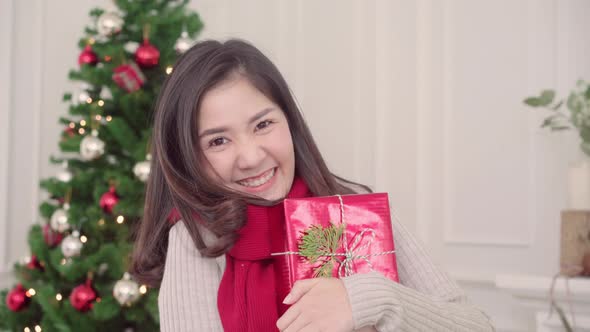 Asian woman holding christmas gifts smiling to camera in Christmas Festival. alt