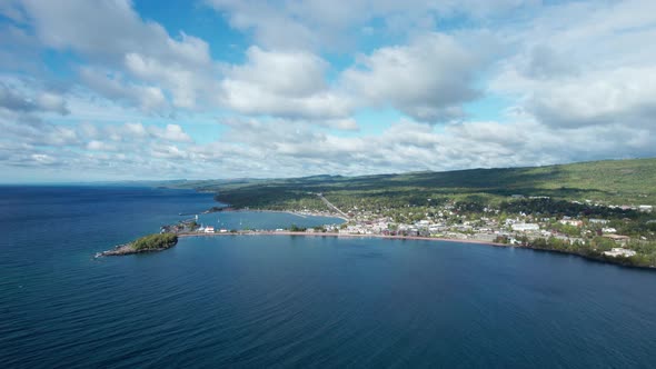 High altitude drone view of cloud shadowsing over trees on a shoreline alt