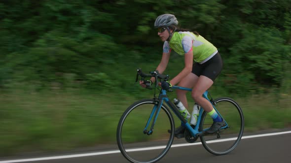 Tracking shot of a female cyclist on country road.  Fully released for commercial use.