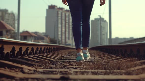 Tourist Legs Walking On Railway Middle Of Rail. Lonely Woman Feet In Jeans Walking On Rail Road. alt