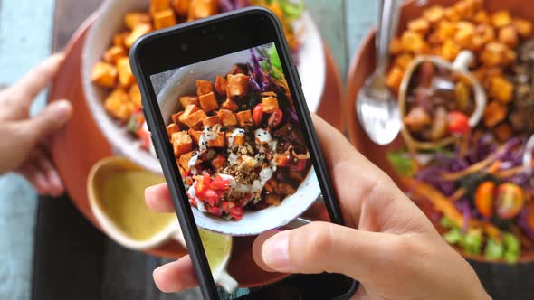 Closeup Of Hands Taking Picture Of Vegan Food Using Cell Phone alt