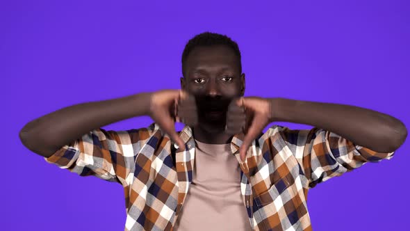 Serious Black Young Millennial Man Shows Refusal Gesture with Thumbs Down Disagree Negative Standing alt