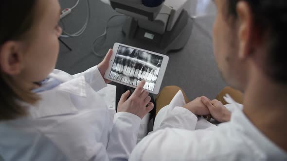 Top Angle Dentist Looking at X-ray on Touchpad alt