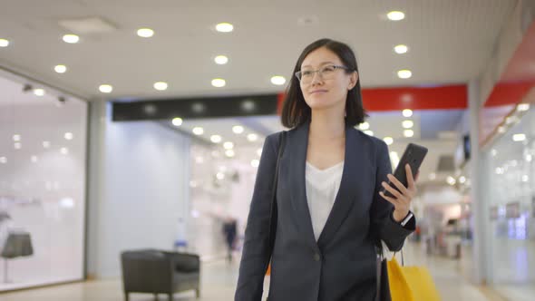 Young Korean Woman Walking through Shopping Mall and Smiling alt