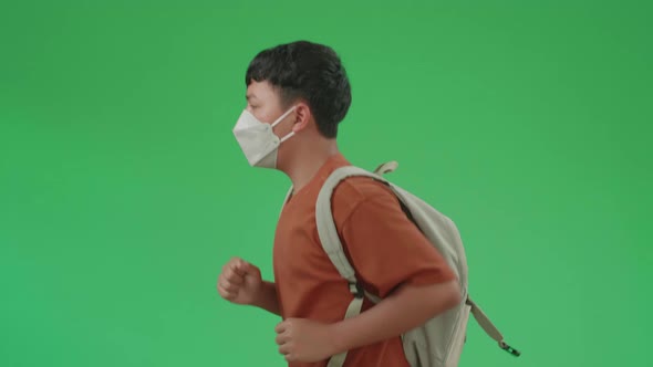 Side View Of Asian Boy Student Wearing A Mask, Running To School On Green Screen Chroma Key alt
