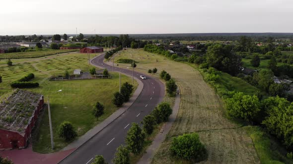 Highway with a Car Near the Dilapidated Buildings of the Old Fortress on the Outskirts of the City alt