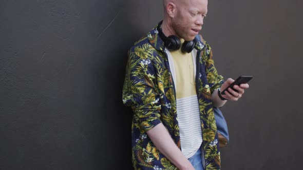 Thoughtful albino african american man with dreadlocks using smartphone alt