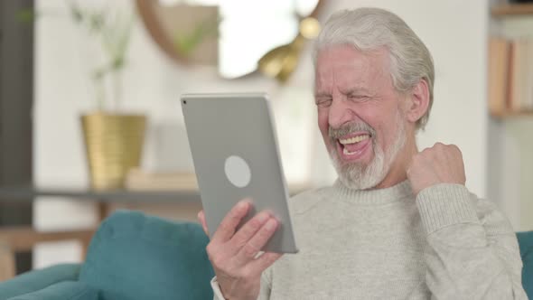 Old Man Celebrating On Tablet on Sofa  alt
