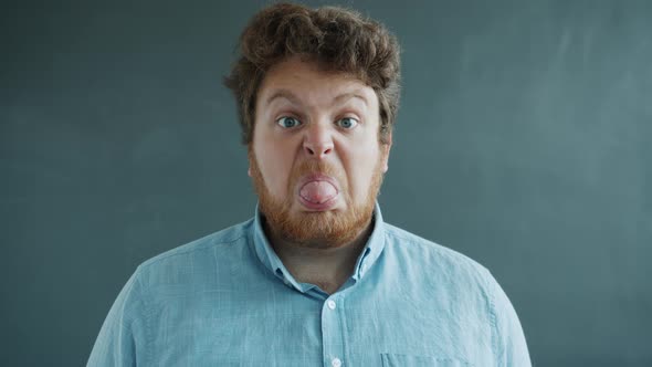 Portrait of Guy Showing Tongue with Hostile Face Then Putting on Glasses and Looking at Camera alt