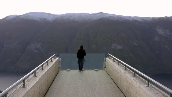 A Tourist Takes in the View from a Lookout Point in Norway alt