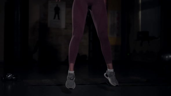 Inspired Sportive Young Slim Woman Jumping Squatting in Slow Motion in Darkness alt