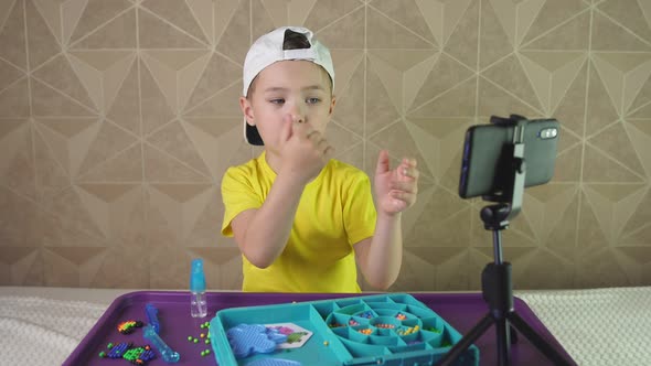 Small Blogger Recording a Video on a Smartphone Emotionally Talks About His Favorite Board Game alt