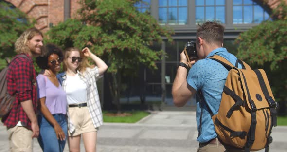Young Man Taking Photo of Smiling Friends Traveling Together in City alt