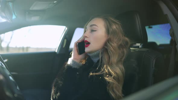 Young Caucasian Brunette Woman Arguing on the Phone Sitting in Car on Driver's Seat alt