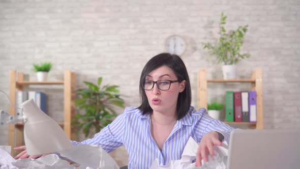Puzzled Young Woman Office Worker and a Heaps of Papers on the Office Desk alt