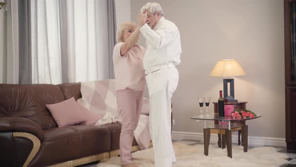 Romantic Dance Of Happy Mature Caucasian Couple Indoors Cheerful Husband Spinning His Lovely 