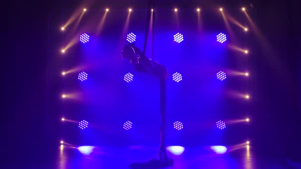 Female Aerial Equilibrium Gymnast Performing Balancing on a Air Silk in a Dark Studio alt