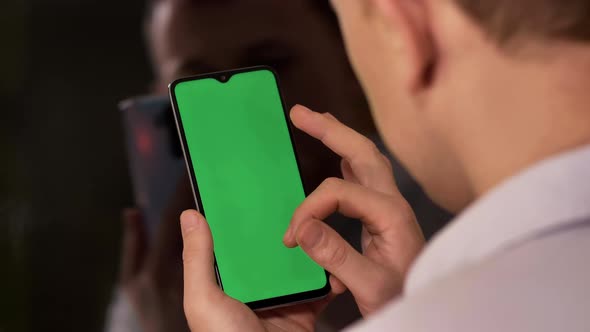 Young Man with a Phone Moves His Finger Across the Screen Chromakey Back View alt