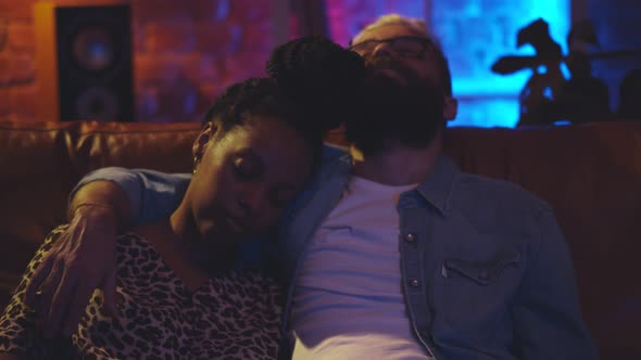 Portrait of Diverse Relaxed Couple Embracing and Sleeping Together on a Couch in Front of Tv alt