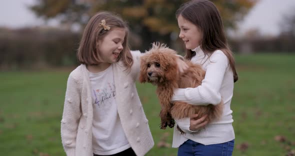 Portrait shot of two little girls smiling and playing together with a dog