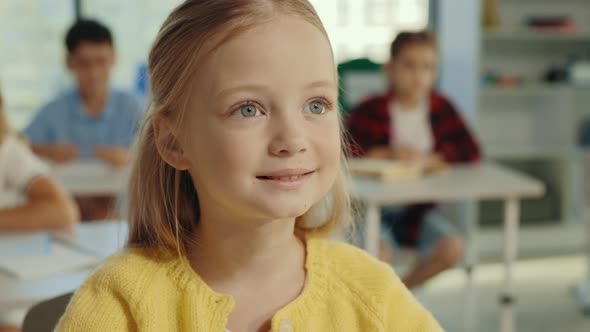 Close Up View of the Beautiful Longhaired Blonde Pupil Girl Looking at the Teacher and Attentively alt