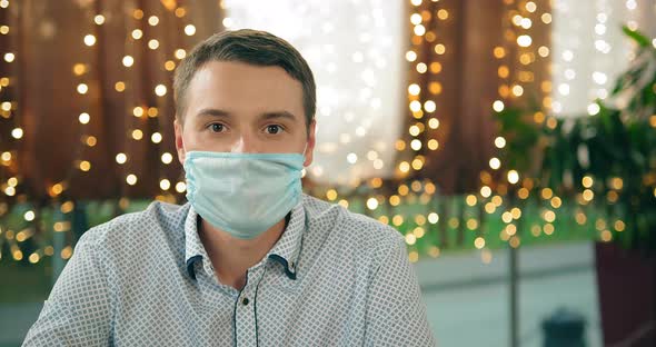 Young Man in Disposable Mask Poses for Camera in Restaurant alt