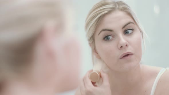 Pretty Young caucasian female applying make up in bathroom