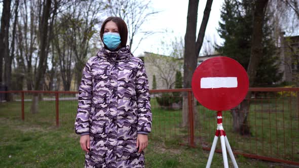 The End of the Pandemic and Virus Spread. A Woman Stays in a Mask Near the Stop Sign and Shows