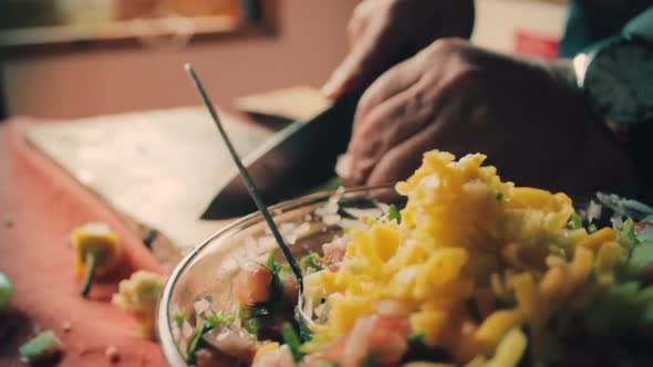 close up of chef's hands cutting and adding vegetables to the salad alt