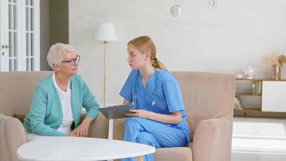Young lady doctor with clipboard talks about tests results with senior grey haired female alt