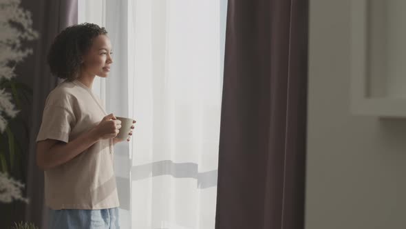 Biracial Girl Drinking Morning Coffee by Window alt