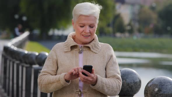 Attractive Old Woman of Retirement Age Using Modern Gadget Scrolling Looking Phone Screen alt