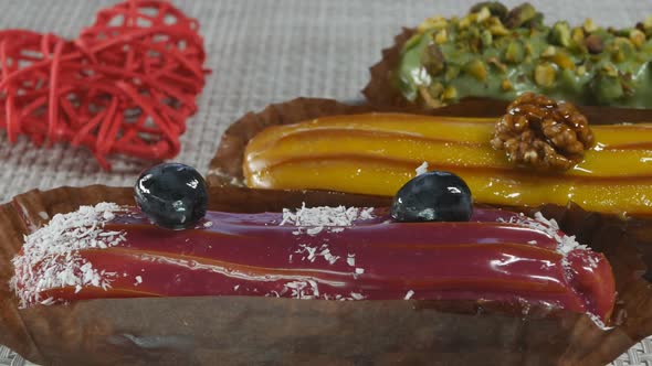 Three Red Yellow and Green Eclairs Custard Cakes with Pistachio Cherry Banana and Passionfruit
