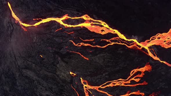 Lava Flow From Black Volcanic Ground On Melted Dark Background - aerial top down alt