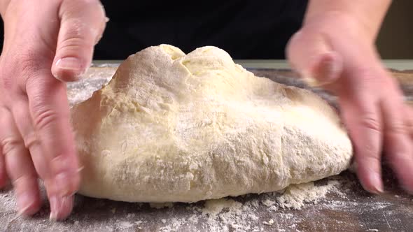 Kneading dough on a wooden board with your hands alt
