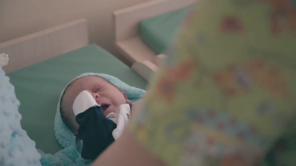 Mommy Puts Little Tuxedo on Newborn Baby on Changing Table alt