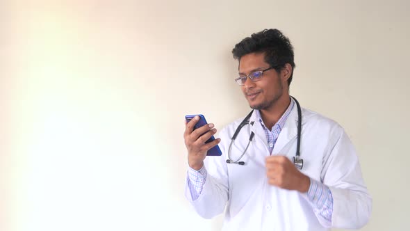 Young Asian Doctor Talking To Smart Shone Camera in Video Chat. alt