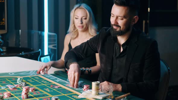 Upper Class Bearded Man with Beauty Woman Are Gambling in a Casino. alt