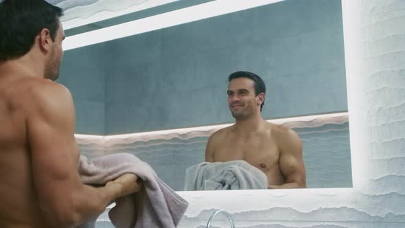 Happy Man Wiping Face with Towel in Bathroom. Handsome Man Feeling Positive. alt