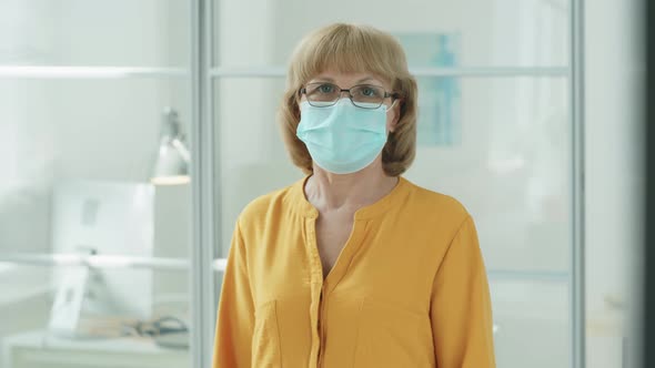 Portrait of Senior Woman in Mask Standing in Clinic alt