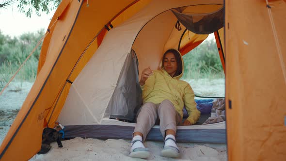 Beautiful Ukrainian Woman in Orange Camping Tent Admiring Morning Sunrise alt