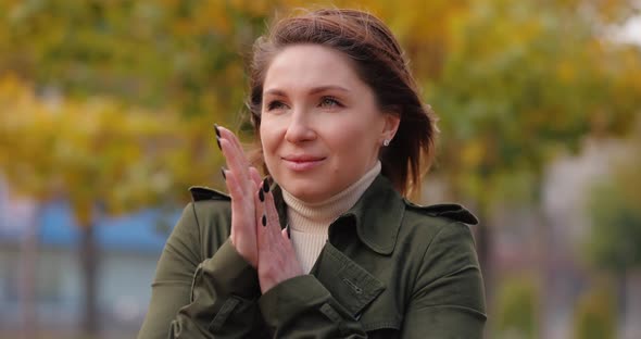 Woman Warming Her Cold Hands at the Autumn Day alt