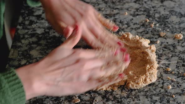 Dolly in of woman hands mixing together pieces of batter to form a cookie dough alt