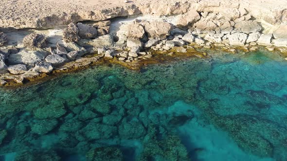 Aerial Top View Footage By Drone of Ocean Blue Water and Rocks A Calm Sea Washes the Rocky Mountain alt