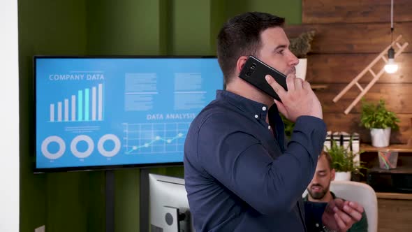 Businessman Talks on the Phone While Walking in the Office alt